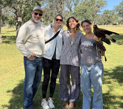 Tod Hirsch and his family outdoors with Diego, a large bird perched on a falconry glove